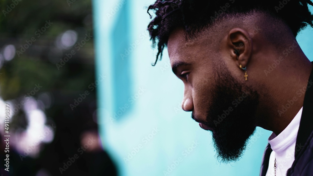 A meditative African person in contemplation leaning on wall outside in street A meditative African person in contemplation leaning on wall outside in street