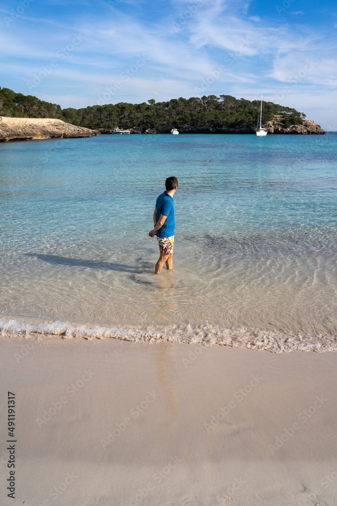 Homme les pieds dans l'eau sur une plage à l'eau transparente