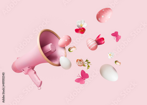Pink megaphone with colorful summer flowers and Easter eggs against pastel blue background. Advertisement idea. Minimal nature concept. Creative banner or announcement of spring holidays.