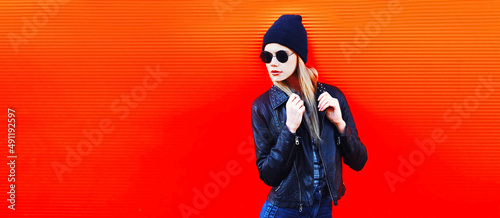 Portrait of stylish blonde young woman in black rock style on vivid background