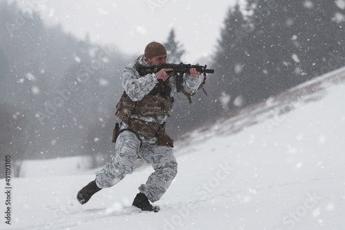 Soldier in winter camouflaged uniform in Modern warfare army on a snow day on forest battlefield with a rifle. Model face very similar to Ukraine prime minister.