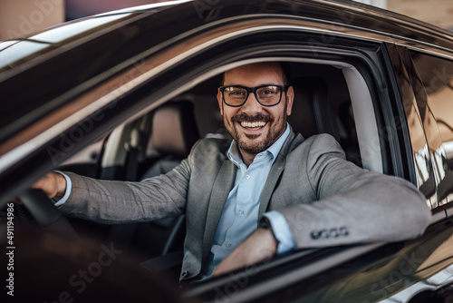Portrait of a happy man, sitting in a car, holding a hand on a s © bnenin