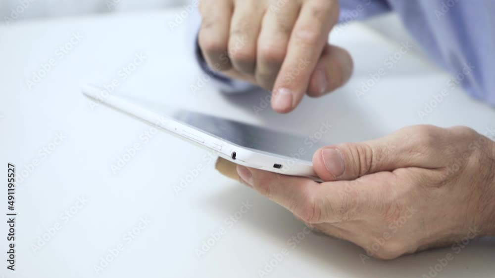 Close-up of an elderly man's old hands using a tablet Close-up of an elderly man's old hands using a tablet
