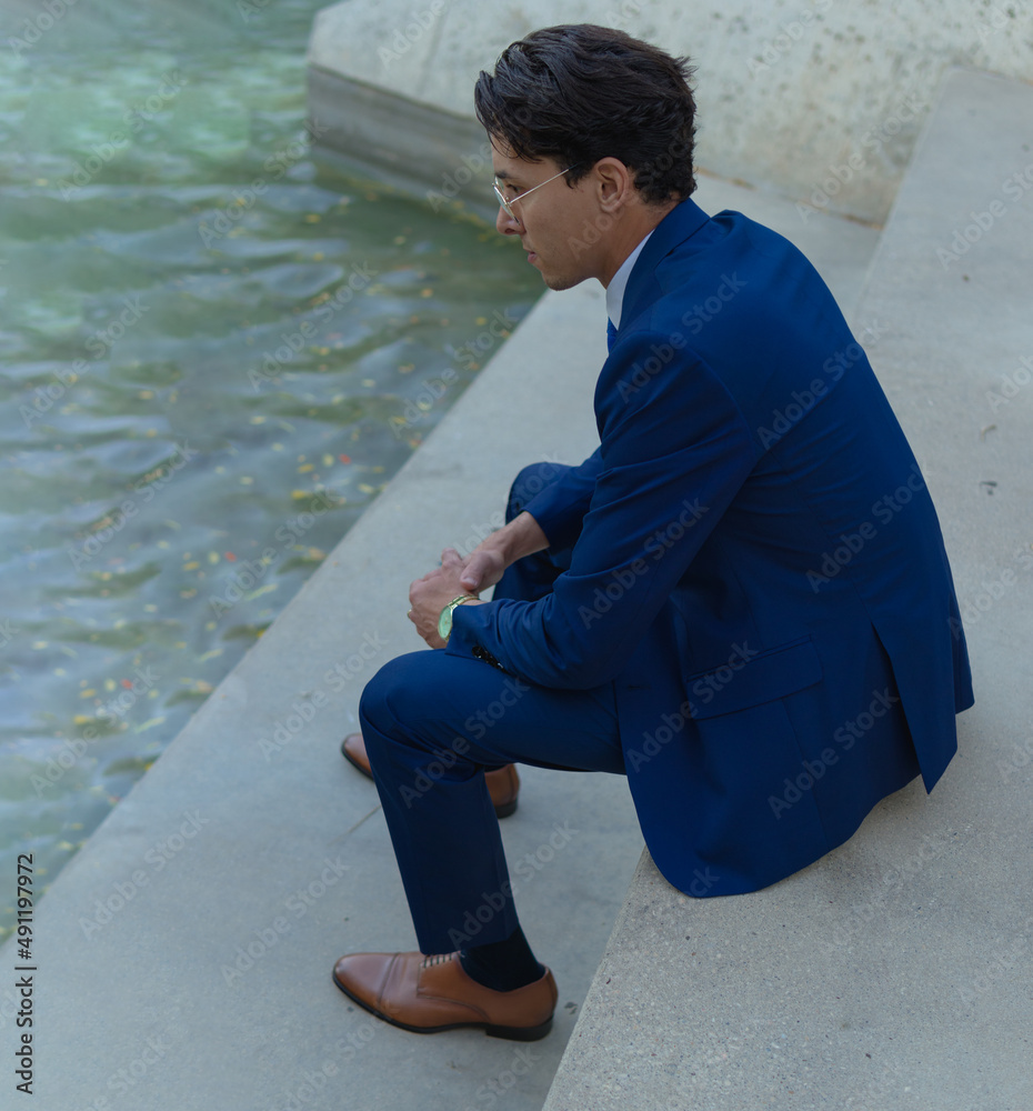 high angle formal portrait of a business man taking a break meditating at the edge of a water pond high angle formal portrait of a business man taking a break meditating at the edge of a water pond