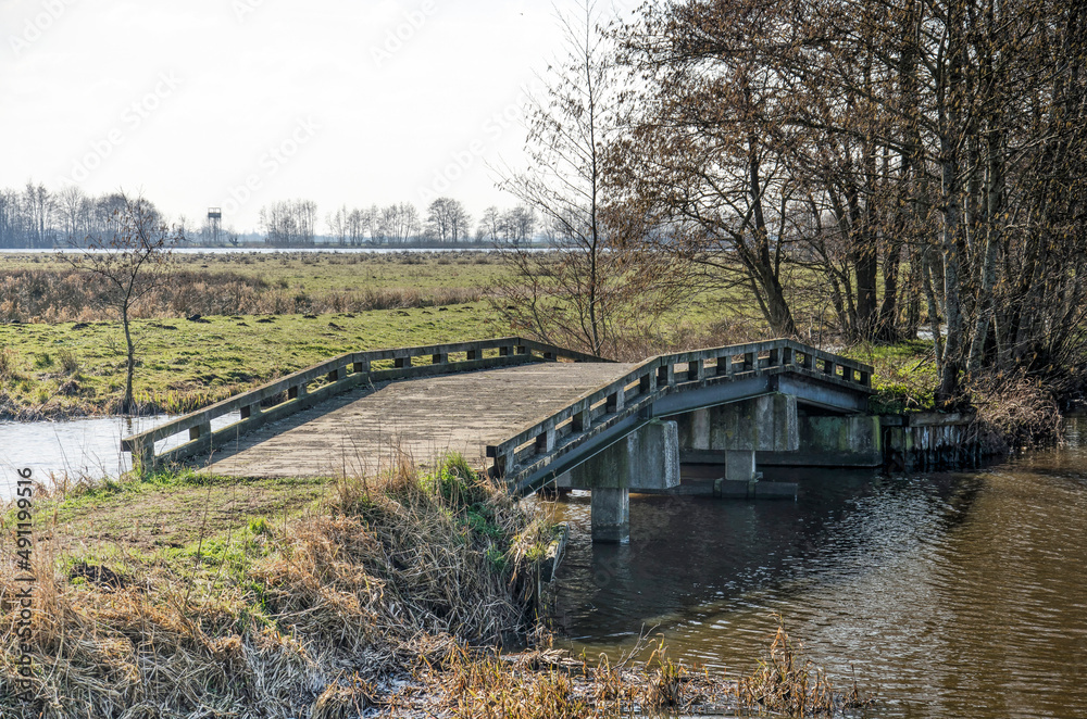 pedestrian bridge made of concrete, steel and wood as part of a hiking trail on a sunny day in early spring in Krimpenerwaard region in the Netherlands