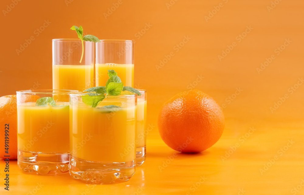Orange juice in glasses and fresh oranges on an orange background. Concept. Photo Orange juice in glasses and fresh oranges on an orange background. Concept. Photo