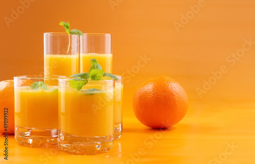Fototapeta Naklejka Na Ścianę i Meble -  Orange juice in glasses and fresh oranges on an orange background. Concept. Photo