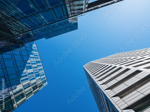 Bottom-up view of modern skyscrapers over blue sky background