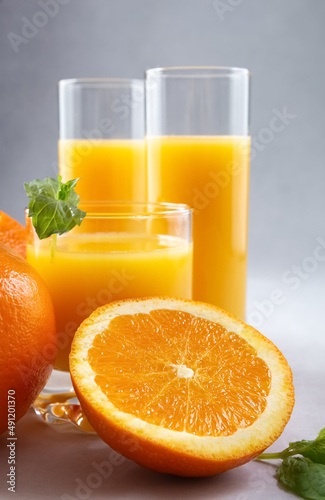 Orange juice in glasses and fresh oranges on a gray background. Concept. Photo