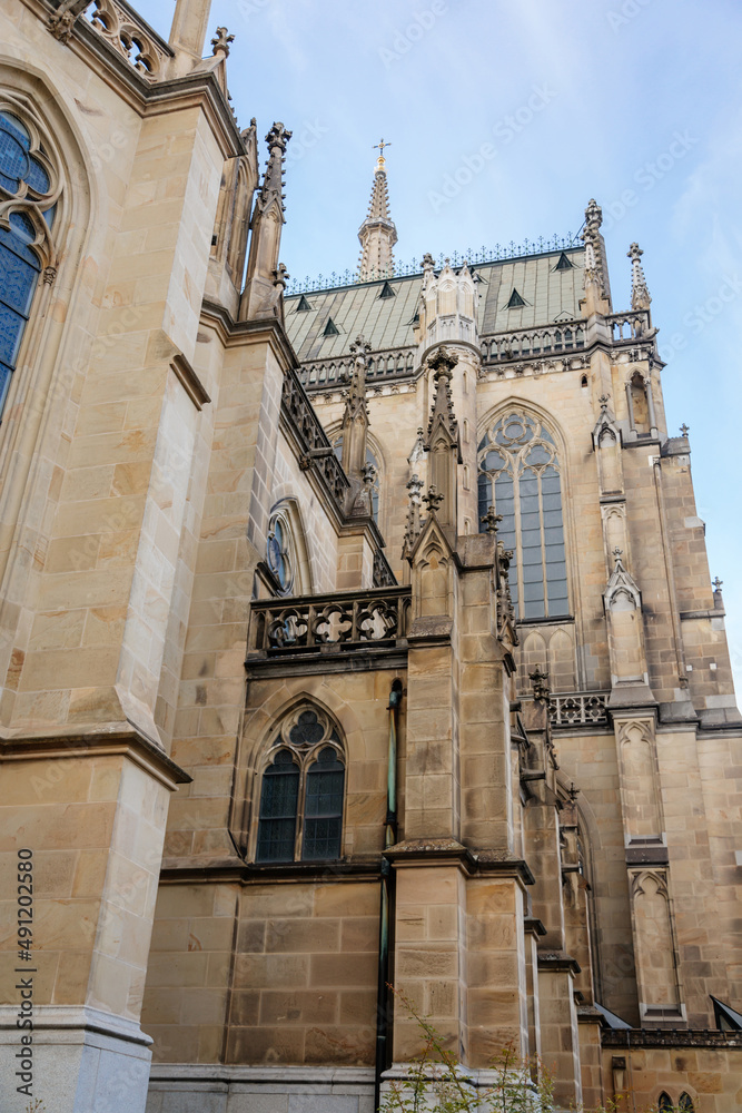 Linz, Austria, 27 August 2021: Facade of medieval catholic stone gothic New Cathedral of Immaculate Conception with arch, old town street at sunny summer day, lancet windows and carved statues