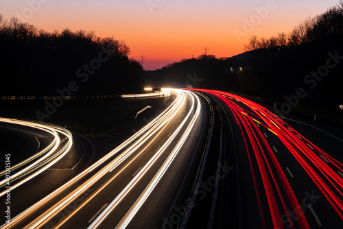 German Autobahn A46 at dusk on a winter evening in Iserlohn Sauerland at junction driveway town centre  long time exposure with light traces of passing car lights. Orange sky gradient after sunset.