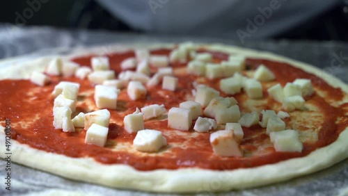 Preparing and adding mozzarella cheese on a pizza dough with tomato sauce photo