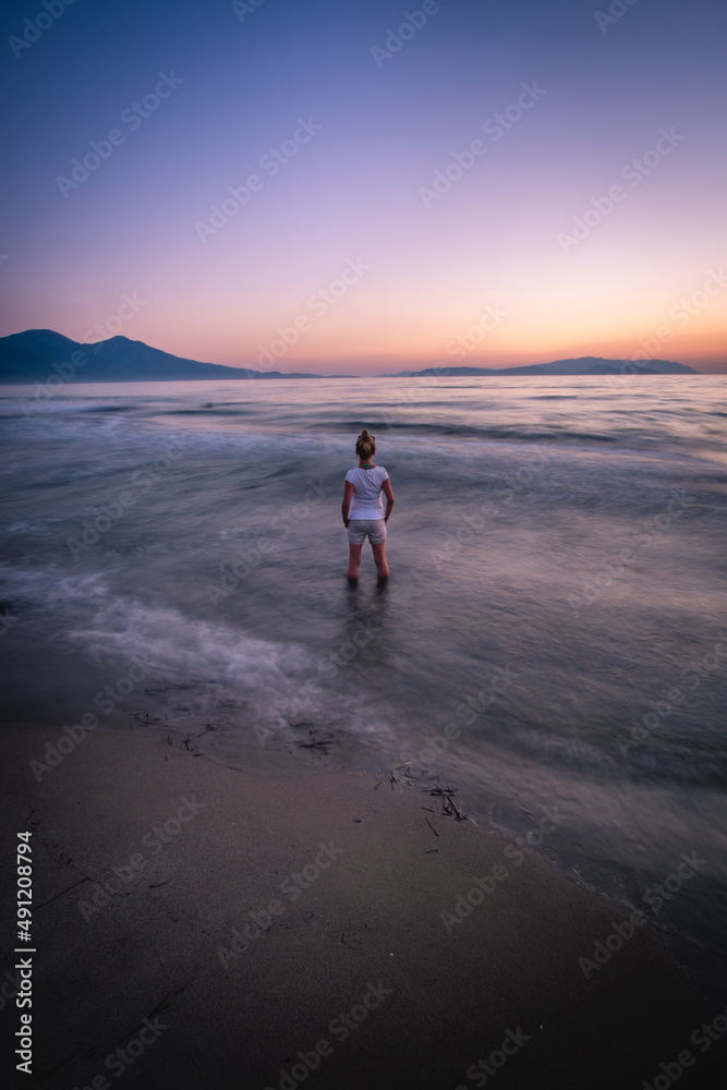 woman standing in the ocean at sunset 