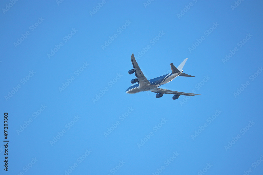 Airplane flying in the clear blue sky, bottom view. Commercial four-engine plane taking off Airplane flying in the clear blue sky, bottom view. Commercial four-engine plane taking off