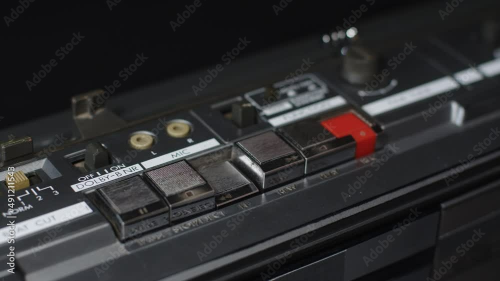 A finger presses the rewind button on a dusty panel on an old tape recorder A finger presses the rewind button on a dusty panel on an old tape recorder