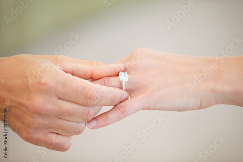 Finding the right one - Marriage and engagement. Cropped view of a mans hand sliding a wedding ring onto a womans ring finger.