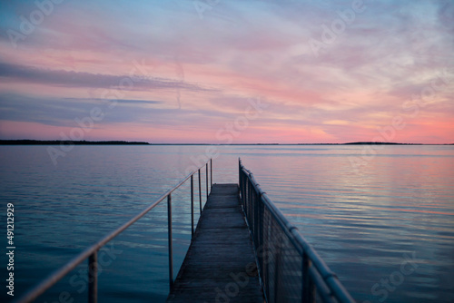 pink sunset at wooden pier on blue sea. view of long jetty stretching to the ocean. water reflection photo