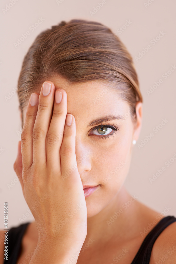 Ive nothing to hide.... Studio portrait of a young woman with one hand over one eye smiling at the camera. Ive nothing to hide.... Studio portrait of a young woman with one hand over one eye smiling at the camera.