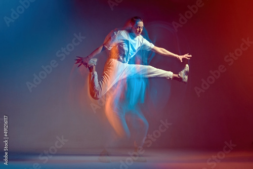 Fotografie Dancing jumping sport girl in leap, performing breakdance in colourful neon light