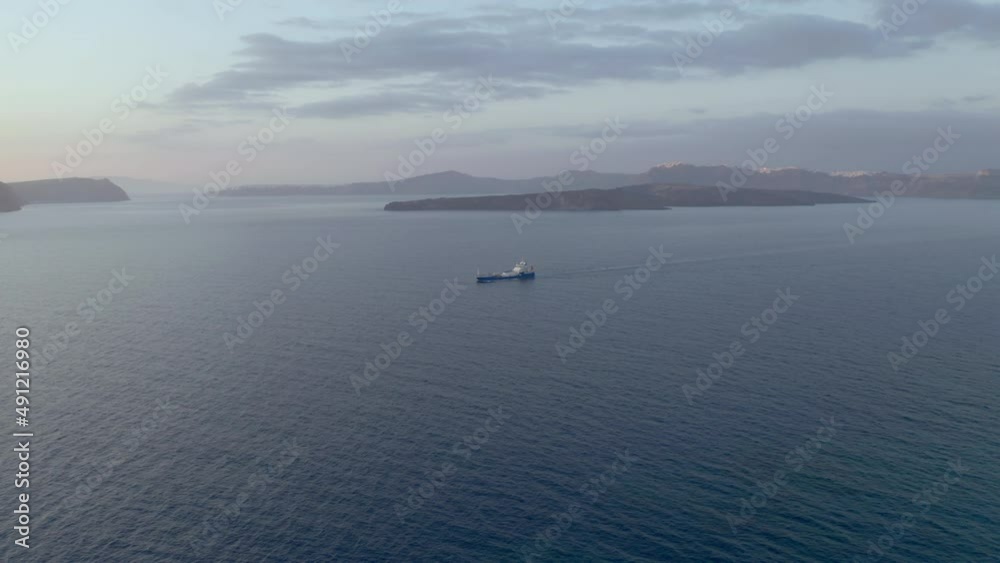 Aerial: Panoramic shot of cargo ship in Santorini, Greece during dusk Aerial: Panoramic shot of cargo ship in Santorini, Greece during dusk