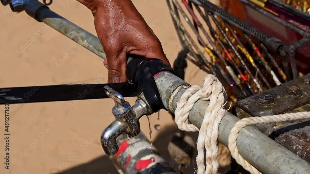 Man fixing leaking tap of the water tanker with a rubber strap Man fixing leaking tap of the water tanker with a rubber strap
