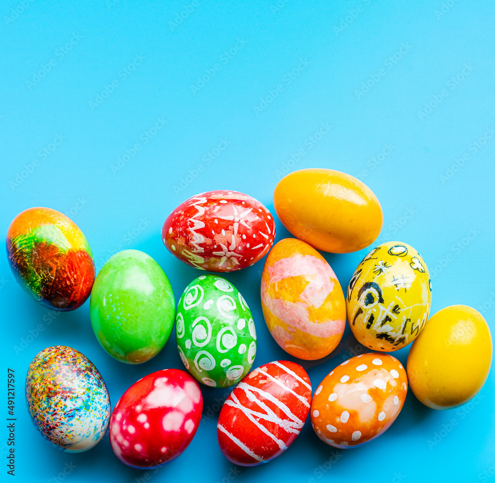 Fototapeta premium closeup, many beautiful painted Easter eggs as blue background. the concept for good friday, easter monday, spring full moon. copy space on top for text or design. top view, nobody, selective focus