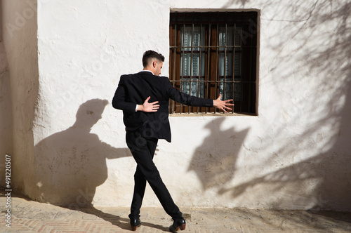 Portrait of young and handsome gipsy man dancing flamenco, dressed in black and green waistcoat dancing flamenco in the typical mediterranean streets of seville. Flamenco cultural heritage of humanity © @skuder_photographer