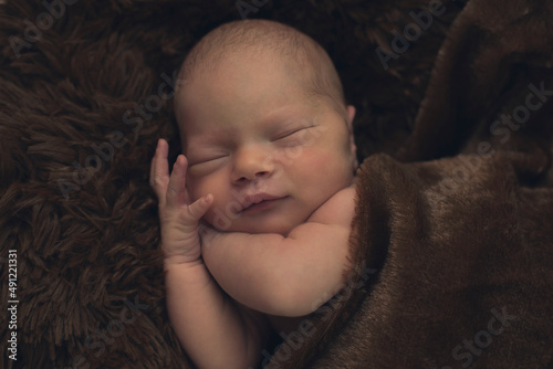 The newborn sleeps in a brown blanket. Happy childhood. Child care. Child
