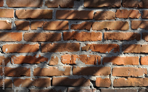An old wall sloppily built of red brick covered with shadow