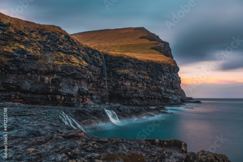 Rocky shore on a cloudy day. Cliffs of Kalsoy island. Early morning in Mikladalur, wild Faroe Islands. November 2021. Long exposure picture