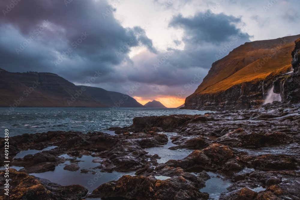 Rocky shore on a cloudy day. Cliffs of Kalsoy island. Early morning in Mikladalur, wild Faroe Islands. November 2021