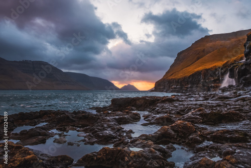 Rocky shore on a cloudy day. Cliffs of Kalsoy island. Early morning in Mikladalur, wild Faroe Islands. November 2021
