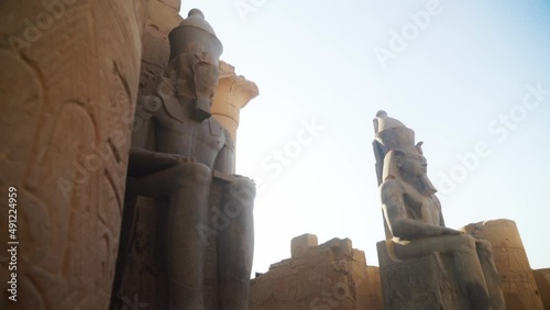 Tall statues in the Karnak Temple, Luxor Egypt. Intricate carved drawings and hieroglyphs adorning the wall.
Slow slide movement sideways.  photo