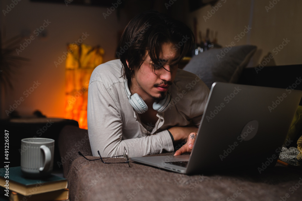 man relaxing on sofa at home and using laptop computer man relaxing on sofa at home and using laptop computer
