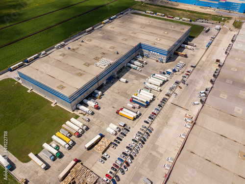 Aerial top view of the large logistics park with warehouse, loading hub with many semi-trailers trucks standing at the ramps for load unload goods.