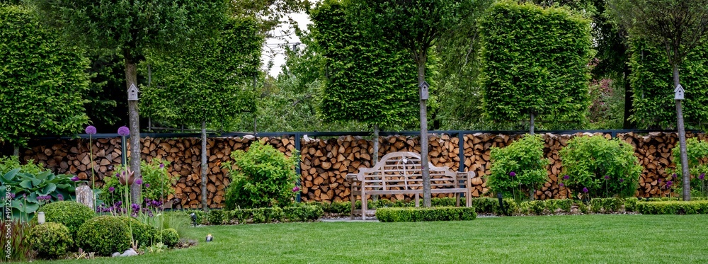 Fototapeta premium Ogród nowoczesny z miejscem do siedzenia. Ławeczka angielska w nowoczesnym zadbanym ogrodzie