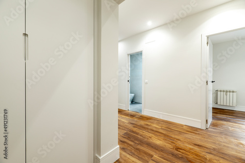 empty room with a built in wardrobe with dark wood doors and oak parquet flooring