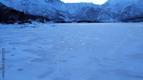 Frozen icy Fjord in Norway - low flyover, harsh winter landscape. SLOW MOTION photo