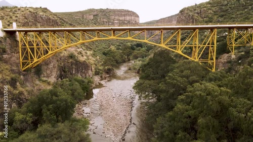 Drone video of a bridge on the highway and below a river between the mountains surrounded by trees in Zimapan Hidalgo, Mexico photo
