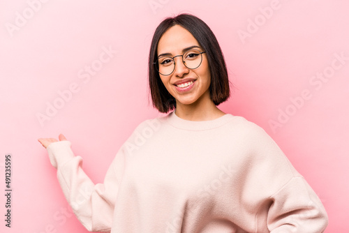 Young hispanic woman isolated on pink background showing a welcome expression.