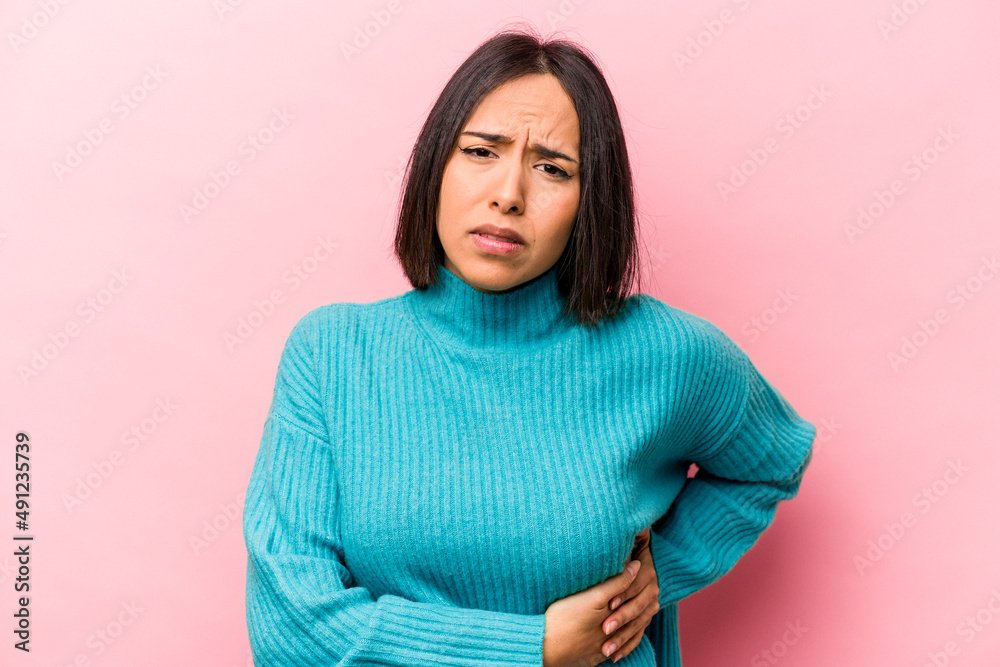 Young hispanic woman isolated on pink background having a liver pain, stomach ache. Young hispanic woman isolated on pink background having a liver pain, stomach ache.