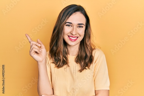 Young hispanic girl wearing casual clothes smiling happy pointing with hand and finger to the side