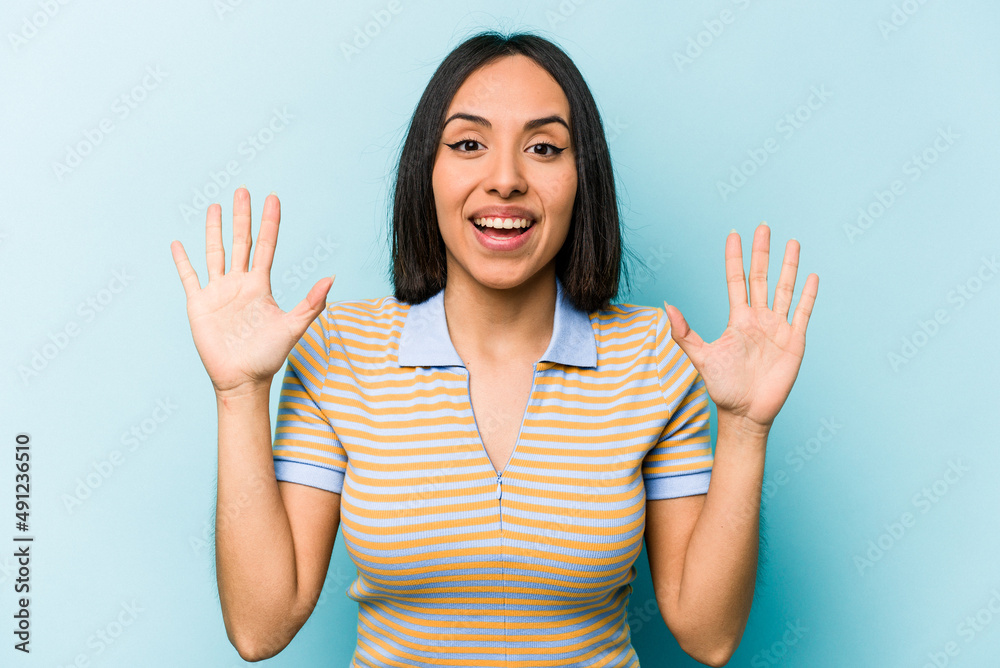 Young hispanic woman isolated on blue background receiving a pleasant surprise, excited and raising hands. Young hispanic woman isolated on blue background receiving a pleasant surprise, excited and raising hands.