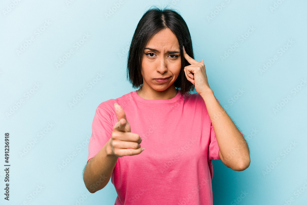 Fototapeta premium Young hispanic woman isolated on blue background pointing temple with finger, thinking, focused on a task.