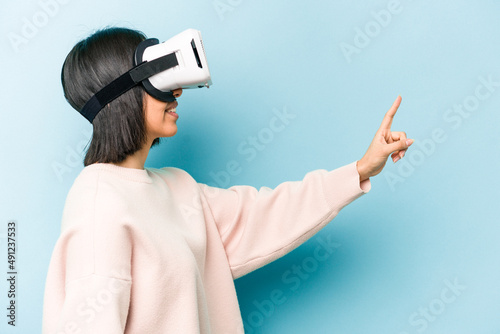 Young hispanic woman wearing a virtual glasses isolated on blue background