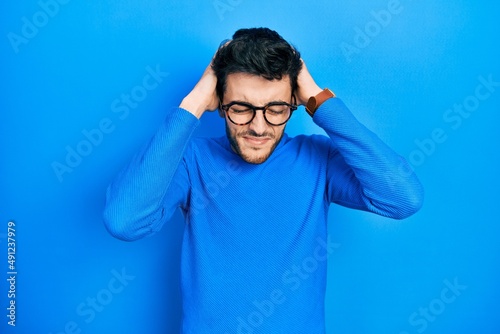 Young hispanic man wearing casual clothes and glasses suffering from headache desperate and stressed because pain and migraine. hands on head. © Krakenimages.com