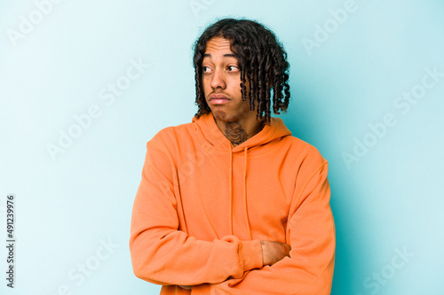 Young African American man isolated on blue background dreaming of achieving goals and purposes