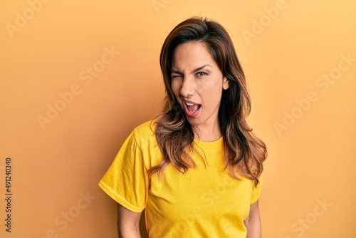 Young latin woman wearing casual clothes winking looking at the camera with sexy expression, cheerful and happy face.