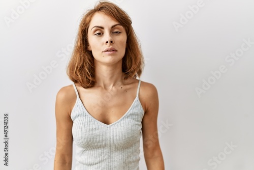 Beautiful caucasian woman standing over isolated background relaxed with serious expression on face. simple and natural looking at the camera.