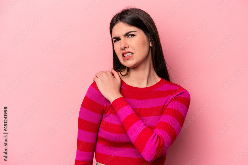 Young caucasian woman isolated on pink background having a shoulder pain. Young caucasian woman isolated on pink background having a shoulder pain.